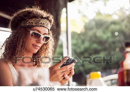 Young woman reading smartphone text at sidewalk cafe View Large Photo Image Stock Photography - Young woman reading smartphone text at sidewalk cafe. Fotosearch