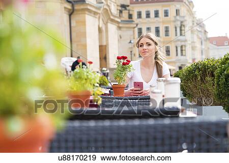 Stock Photo - Young woman sitting at outdoor cafe. Fotosearch