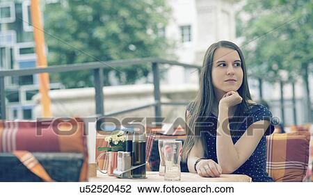 Young woman sitting at table in outdoor cafe View Large Photo Image Stock Image - Young woman sitting at table in outdoor cafe. Fotosearch
