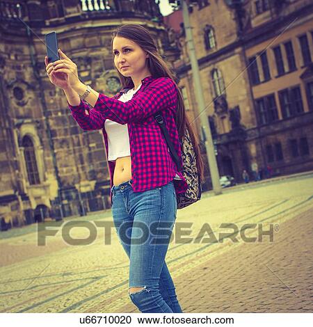 Stock Image - Young woman taking photo of herself. Fotosearch