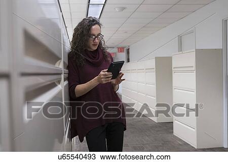 Young woman using digital tablet in corridor View Large Photo Image Stock Image - Young woman using digital tablet in corridor. Fotosearch