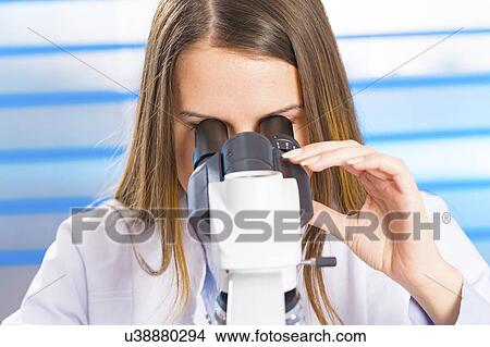Picture - Young woman using microscope. Fotosearch