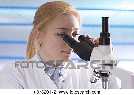 Stock Image - Young woman using microscope. Fotosearch