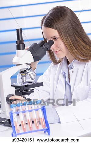Stock Image - Young woman using microscope. Fotosearch