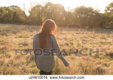 Young woman walking through field in autumn, rear view View Large Photo Image Stock Photograph - Young woman walking through field in autumn, rear view. Fotosearch