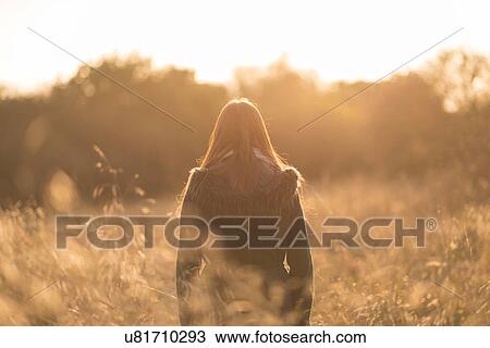 Young woman walking through field, rear view View Large Photo Image Stock Image - Young woman walking through field, rear view. Fotosearch