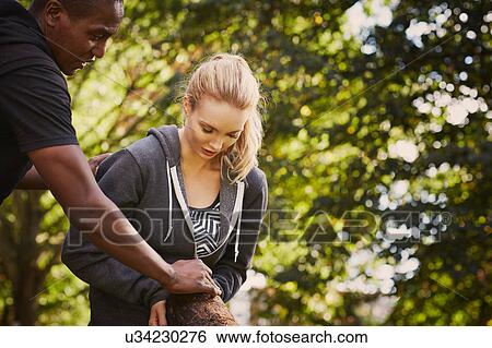Young woman with personal trainer explaining tree trunk lift in park View Large Photo Image Stock Photograph - Young woman with personal trainer explaining tree trunk lift in park. Fotosearch