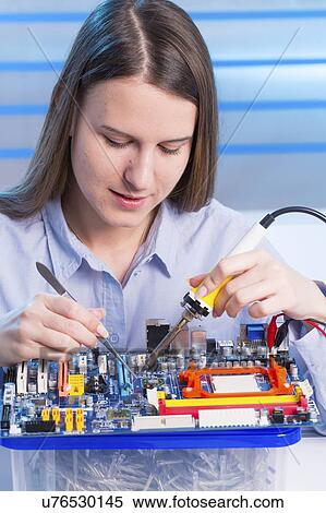 Stock Photography - Young woman working on circuit board. Fotosearch
