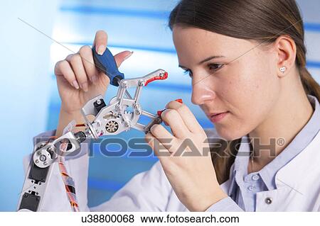 Stock Photo - Young woman working on robotic arm. Fotosearch