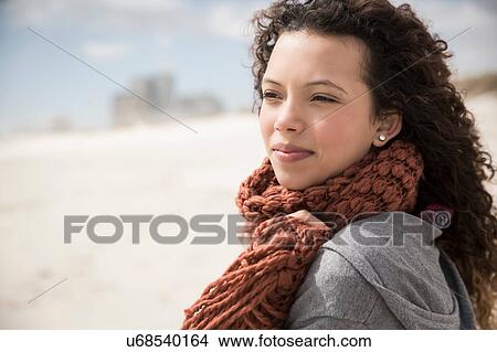 Picture - Young woman wrapped in scarf looking out to sea from beach, Western Cape, South Africa. Fotosearch