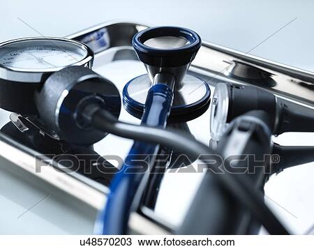Stock Image - Close-up of a sphygmomanometer, stethoscope and otoscope on a metal tray.. Fotosearch