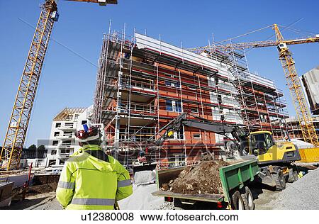 Construction worker on a site with cranes. View Large Photo Image Stock Photo - Construction worker on a site with cranes.. Fotosearch