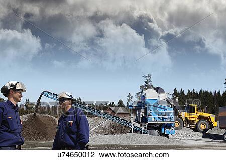 Stock Image - MODEL RELEASED. Construction workers on site with bulldozers.. Fotosearch