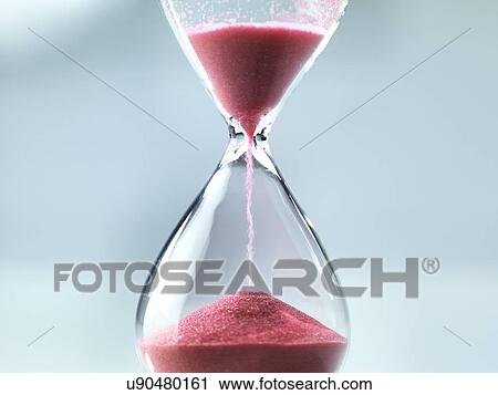Stock Image - Sand flowing through an hourglass.. Fotosearch