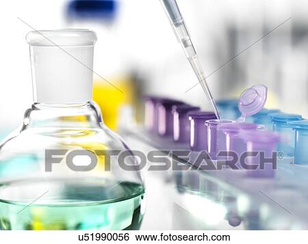 Stock Photograph - Substance being pipetted from a round-bottom flask into Eppendorf tubes.. Fotosearch