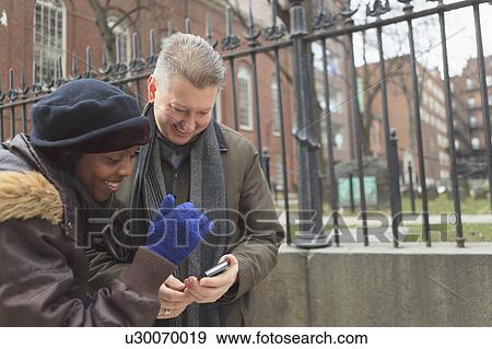 Stock Photo - Couple looking at pictures on a cell phone. Fotosearch