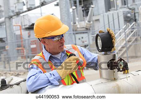Stock Image - Electrical engineer examining pressure sensor. Fotosearch