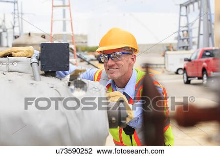 Stock Image - Electrical engineer examining pressure sensor. Fotosearch