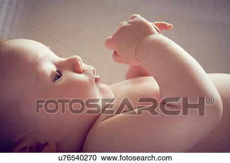 Stock Image - Alert baby boy lying on back in crib. Fotosearch