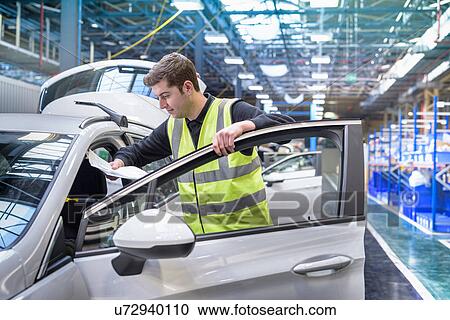 Stock Image - Apprentice car inspector in car factory. Fotosearch