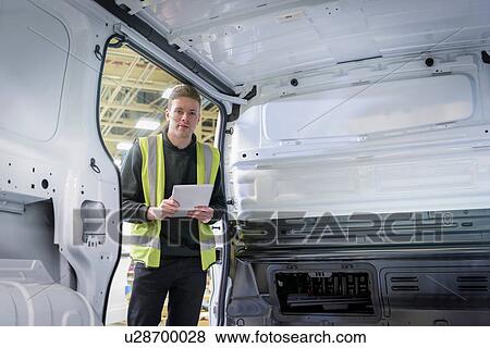 Stock Photo - Apprentice vehicle inspector inspecting interior of vehicle in car factory, portrait. Fotosearch