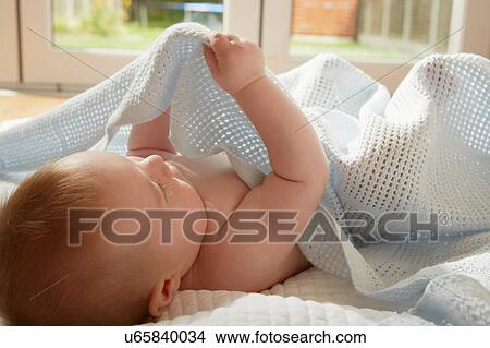 Baby boy lying on back playing with blanket View Large Photo Image Picture - Baby boy lying on back playing with blanket. Fotosearch