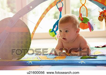 Stock Photograph - Baby boy lying on play mat staring. Fotosearch