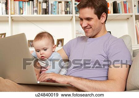 Baby girl helping father with laptop typing on sofa View Large Photo Image Stock Photo - Baby girl helping father with laptop typing on sofa. Fotosearch