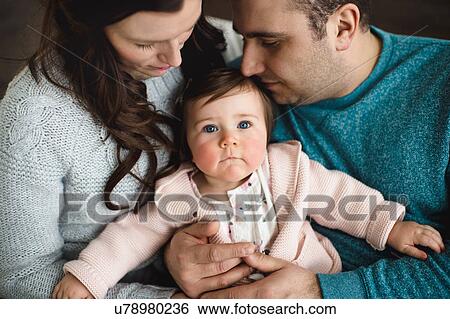 Baby girl looking up while being snuggled by her parents View Large Photo Image Stock Photograph - Baby girl looking up while being snuggled by her parents. Fotosearch