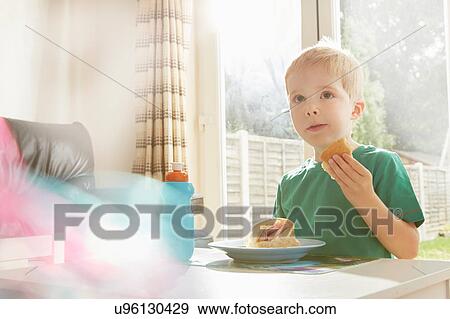 Boy eating sandwich at table View Large Photo Image Stock Photo - Boy eating sandwich at table. Fotosearch