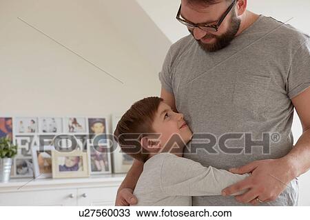 Boy hugging father in living room View Large Photo Image Stock Image - Boy hugging father in living room. Fotosearch