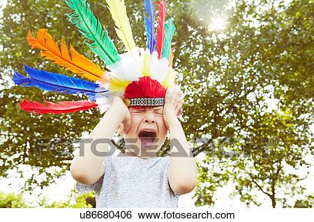 Boy in feather headdress screaming in garden View Large Photo Image Stock Photograph - Boy in feather headdress screaming in garden. Fotosearch