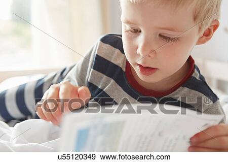Stock Photo - Boy lying on bed reading a book. Fotosearch