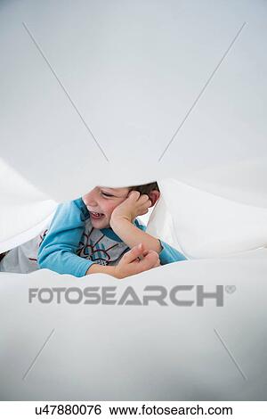 Boy lying on side between white bed sheets View Large Photo Image Stock Photograph - Boy lying on side between white bed sheets. Fotosearch