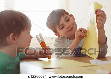 Boy showing brother drawing at table View Large Photo Image Picture - Boy showing brother drawing at table. Fotosearch