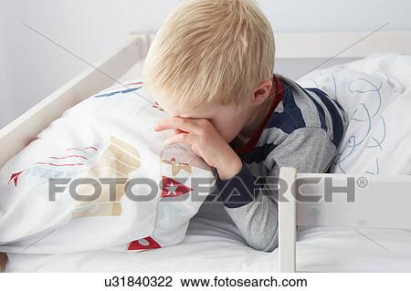 Stock Image - Boy waking up in bed. Fotosearch