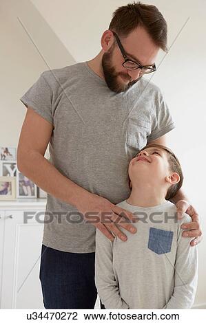 Stock Image - Boy with father's hands on shoulders. Fotosearch