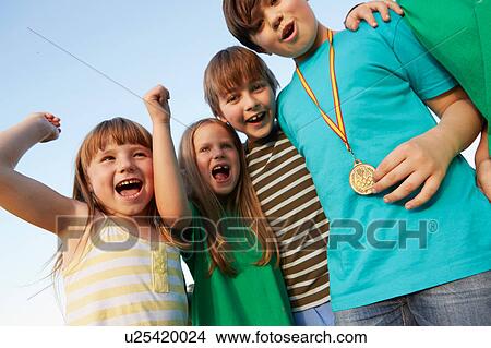 Picture - Boy with gold medal and team cheering against blue sky. Fotosearch