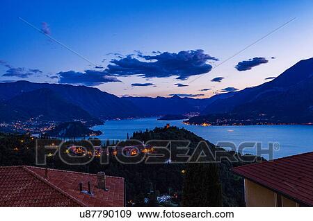 Stock Photo - Buildings illuminated in the evening by Lake Como, Varenna, Italy. Fotosearch
