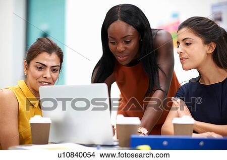 Business women in meeting looking at laptop View Large Photo Image Picture - Business women in meeting looking at laptop. Fotosearch