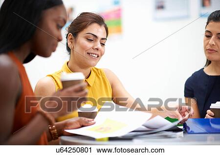 Stock Image - Business women with paperwork in meeting. Fotosearch