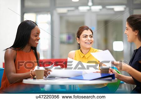 Stock Photograph - Business women with paperwork in meeting. Fotosearch