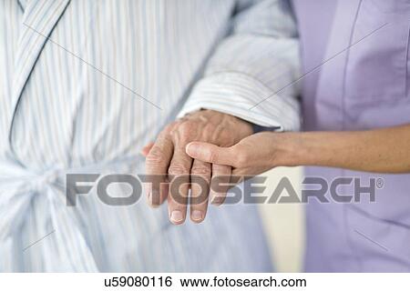Stock Photograph - Care worker holding senior patient's hand. Fotosearch