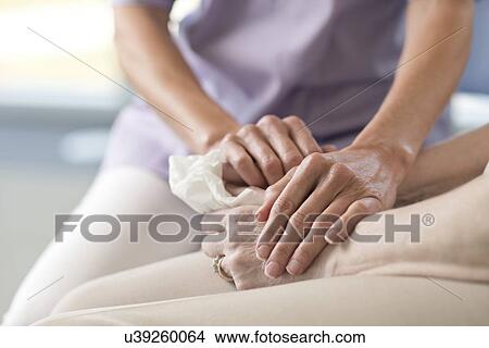 Picture - Care worker holding senior woman's hands. Fotosearch