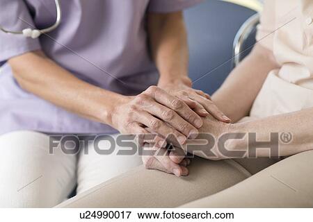 Stock Photo - Care worker holding senior woman's hands. Fotosearch