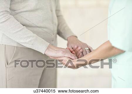 Stock Photography - Care worker holding senior woman's hands. Fotosearch