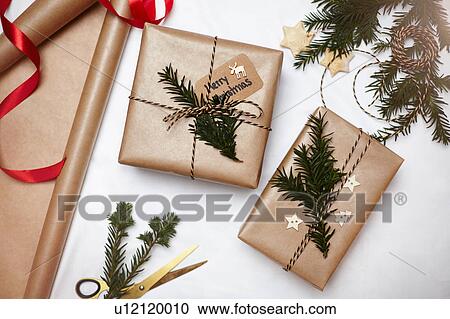 Christmas gifts wrapped in brown paper, decorated with fern and string, overhead view View Large Photo Image Stock Image - Christmas gifts wrapped in brown paper, decorated with fern and string, overhead view. Fotosearch