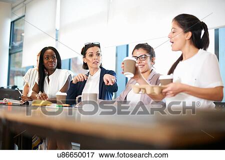 Stock Photo - Colleagues having meeting at conference room table. Fotosearch