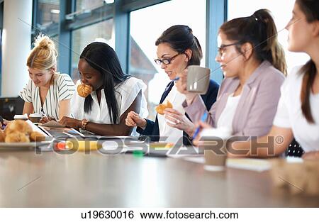 Stock Photograph - Colleagues having meeting at conference room table. Fotosearch