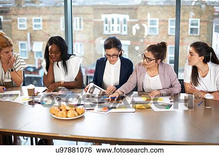 Stock Photograph - Colleagues having meeting at conference room table. Fotosearch